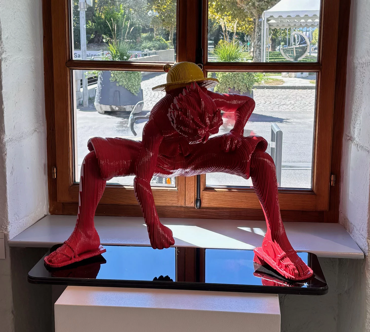 Sculpture Luffy de One Piece en layer art rouge saumoné, chapeau de paille jaune, jambes écartées
