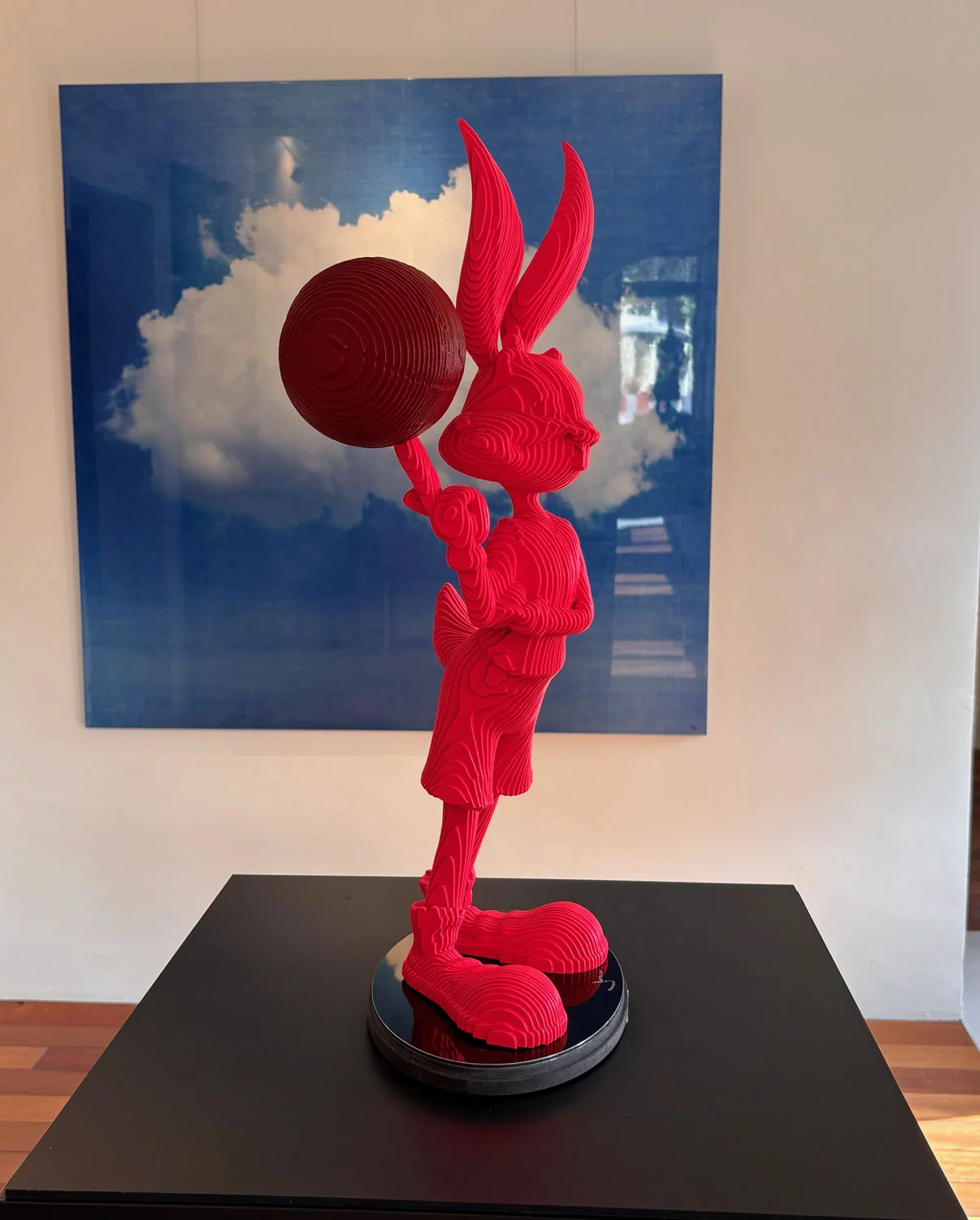 Sculpture Bugs Bunny Space Jam en layer art rouge vif, ballon de basket en équilibre sur le doigt